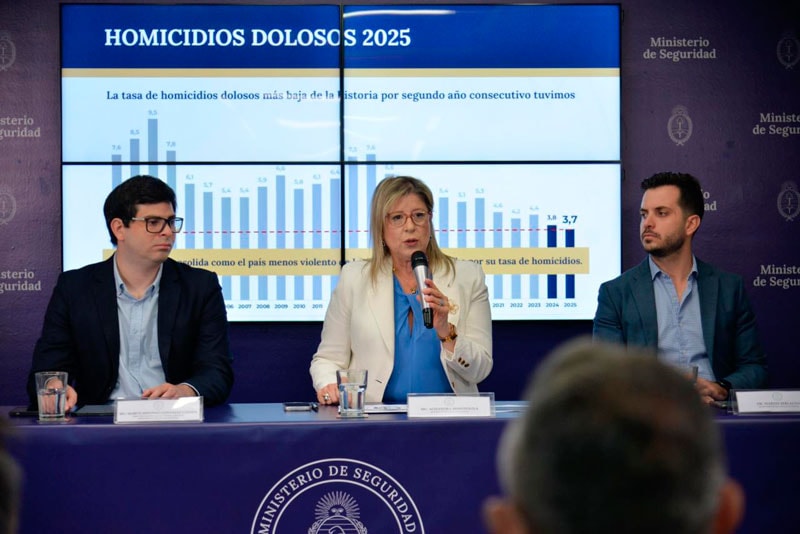 Alejandra Monteoliva, de frente, habla con un micrófono sentada entre dos funcionarios durante una presentación de estadísticas.