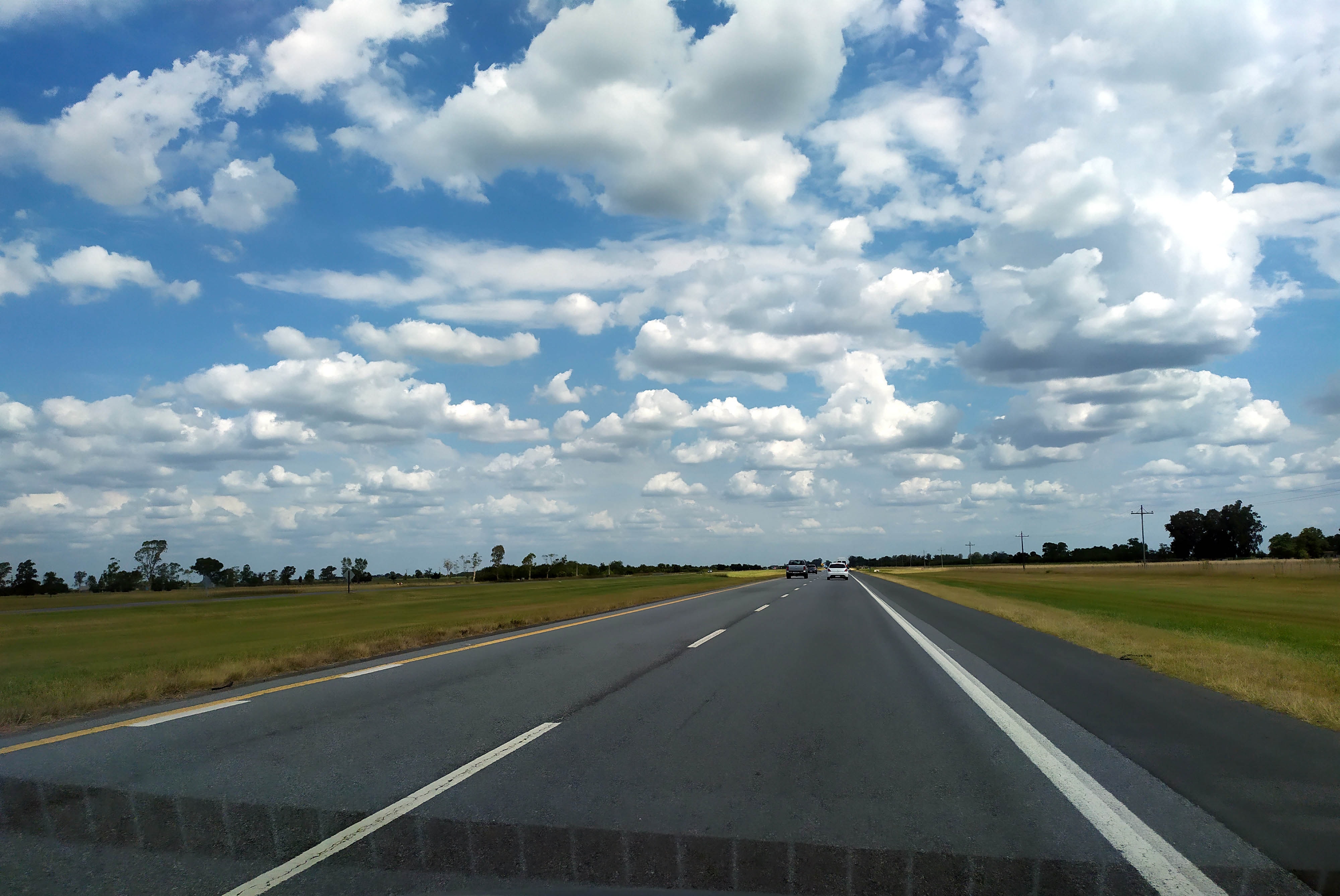 Vista desde el interior de un auto de los dos carriles de la Autovía 2, con vehículos adelante y cielo con nubes